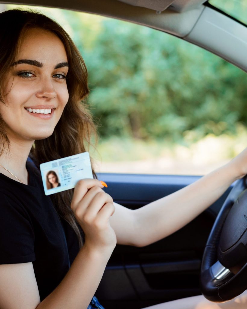 Student in a modern car showing driving licence